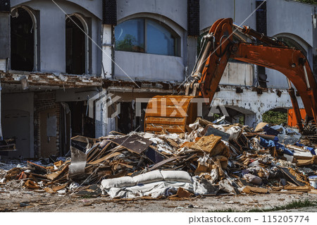 Old excavator removes a pile of construction debris from the demolition of an old house. Chaos, destruction, disorder Old excavator removes a pile of construction debris from the demolition of an old house. Chaos, destruction, disorder 115205774
