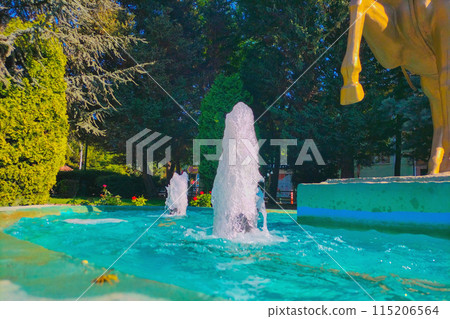 A fountain with an azure pool on a sunny pleasant day, with a slight haze and blur with interesting bubbles in the water in flight A fountain with an azure pool on a sunny pleasant day, with a slight haze and blur with interesting bubbles in the water in flight 115206564