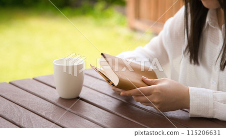 A young woman reading a book in an open cafe A young woman reading a book in an open cafe 115206631