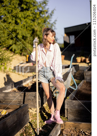 Young woman works on her backyard garden, 115206804