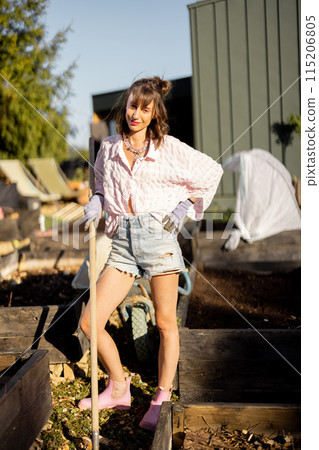 Young woman works on her backyard garden, 115206805