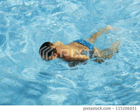 A tanned child swims in a pool with clear water. 115206831