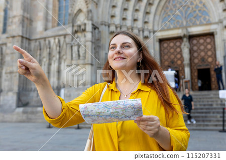 Young woman tourist with paper map standing in front of the famous saint Eulalia church in Barcelona. Concept of travel, tourism and vacation in city. Cathedral of Barcelona Young woman tourist with paper map standing in front of the famous saint Eulalia church in Barcelona. Concept of travel, tourism and vacation in city. Cathedral of Barcelona 115207331