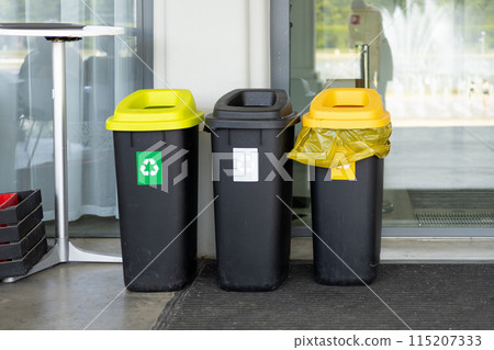 Colorful trash cans for sorting garbage. For plastic, glass, paper and others waste. Waste containers for garbage segregation in Poland, standing next to a wall 115207333