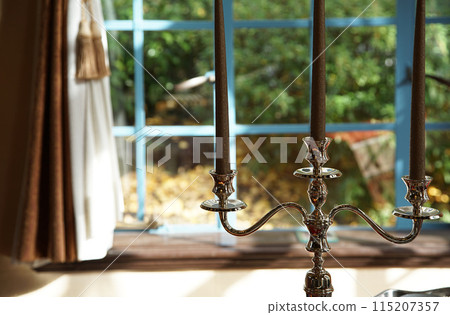Candle stand by the window on a sunny day Candle stand by the window on a sunny day 115207357