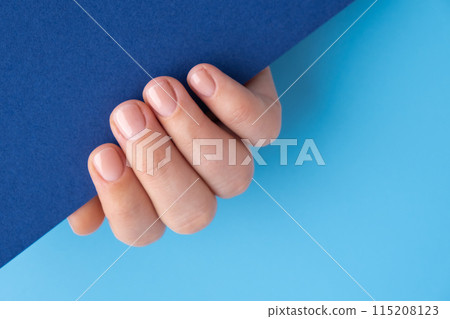 Stylish nude beige female nails on blue background. Mock up template copy space Modern trendy stylish Beautiful manicure. Cute pastel nail minimalistic design concept of beauty treatment. Gel nails 115208123
