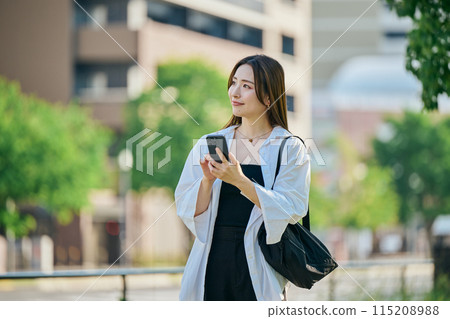 一個操作智能手機的年輕女子 一個操作智能手機的年輕女子 115208988
