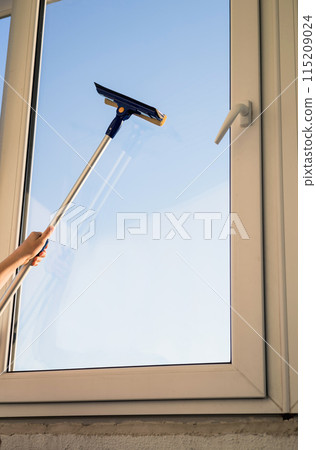 Hand with mop washes the glass of the windows 115209024