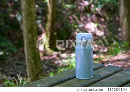 山路上的長椅上放著一個淺藍色水瓶 115209194