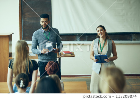 Two teachers, man and woman standing in university classroom and leading meeting with students. Talking about upcoming exams 115209874