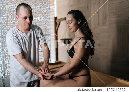 Pretty relaxed woman getting professional massage of palm from male massage therapist in wellness center.. Masseur using acupressure techniques at spa. Concept of healthy lifestyle and body care. 115210212