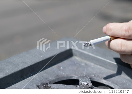 A lit cigarette and an ashtray A lit cigarette and an ashtray 115210347