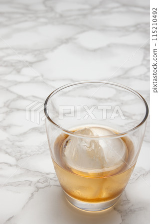 Round ice cubes of whiskey on the rocks and a marble table Round ice cubes of whiskey on the rocks and a marble table 115210492