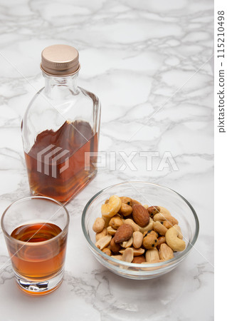 Whiskey mini bottle, shot glass and snacks on marble 115210498