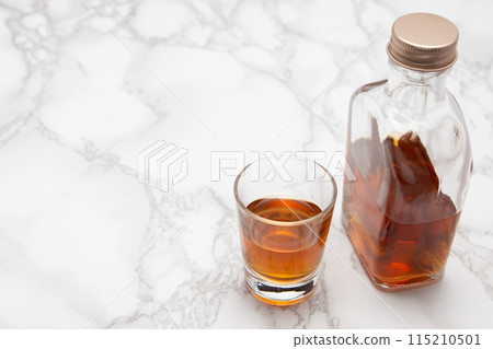 大理石桌上的威士忌迷你瓶和一個小玻璃杯 大理石桌上的威士忌迷你瓶和一個小玻璃杯 115210501