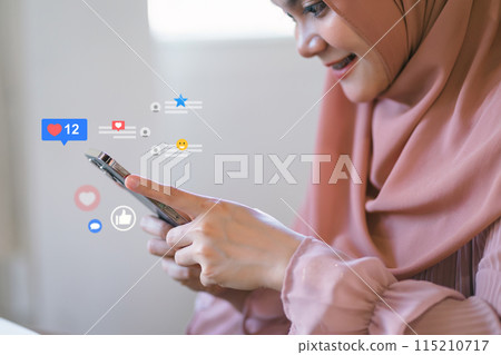 Smiling woman in hijab engaging with social media on smartphone Smiling woman in hijab engaging with social media on smartphone 115210717