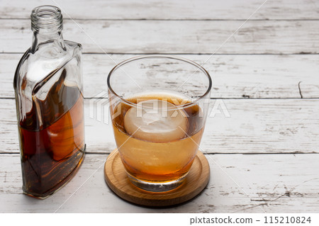 Round ice cubes on the rocks and a bottle of whiskey 115210824