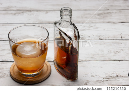 Round ice cubes on the rocks and a bottle of whiskey 115210830