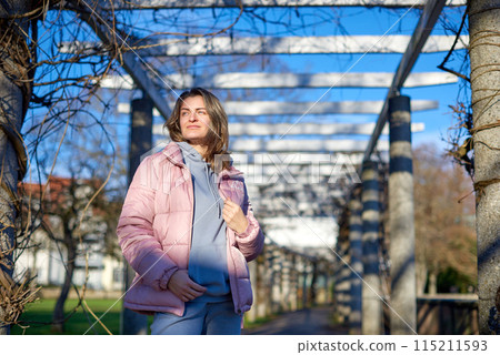 Winter Fun in Bitigheim-Bissingen: Beautiful Girl in Pink Jacket Amidst Half-Timbered Charm. a lovely girl in a pink winter jacket standing in the archway of the historic town of Bitigheim-Bissingen 115211593