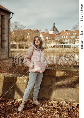 Young beautiful pretty tourist girl in warm hat and coat with backpack walking at cold autumn in Europe city enjoying her travel in Bietigheim-Bissingen, Deutschland. Outdoor portrait of young tourist Young beautiful pretty tourist girl in warm hat and coat with backpack walking at cold autumn in Europe city enjoying her travel in Bietigheim-Bissingen, Deutschland. Outdoor portrait of young tourist 115211606