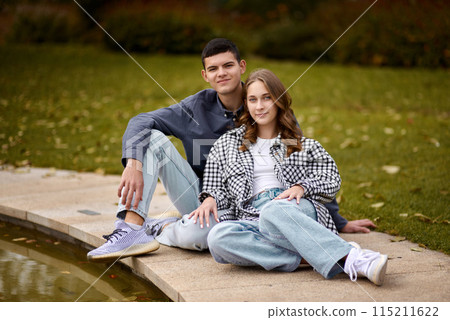Young couple kissing and rejoices at the lake. lovely young couple kissing outdoors in autumn. Loving couple walking in nature. Autumn mood. Happy man and woman hugging and kissing in autumn. Love Young couple kissing and rejoices at the lake. lovely young couple kissing outdoors in autumn. Loving couple walking in nature. Autumn mood. Happy man and woman hugging and kissing in autumn. Love 115211622