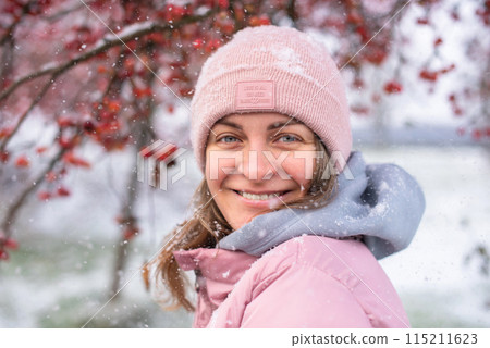 Winter Elegance: Portrait of a Beautiful Girl in a Snowy European Village. Winter lifestyle portrait of cheerful pretty girl. Smiling and having fun in the snow park. Snowflakes falling down Winter Elegance: Portrait of a Beautiful Girl in a Snowy European Village. Winter lifestyle portrait of cheerful pretty girl. Smiling and having fun in the snow park. Snowflakes falling down 115211623