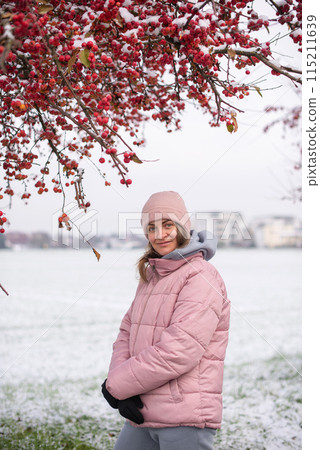 Winter Elegance: Portrait of a Beautiful Girl in a Snowy European Village. Winter lifestyle portrait of cheerful pretty girl. Smiling and having fun in the snow park. Snowflakes falling down Winter Elegance: Portrait of a Beautiful Girl in a Snowy European Village. Winter lifestyle portrait of cheerful pretty girl. Smiling and having fun in the snow park. Snowflakes falling down 115211639
