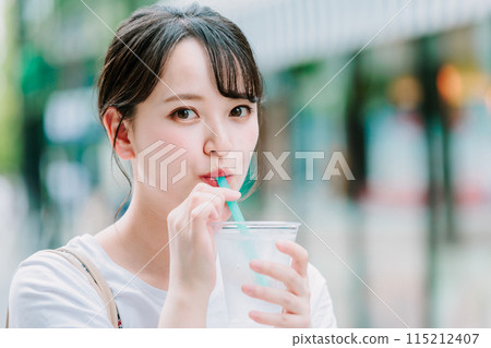 Young woman drinking water outdoors Young woman drinking water outdoors 115212407