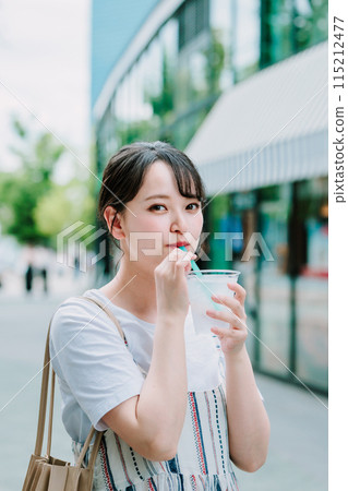Young woman drinking water outdoors 115212477