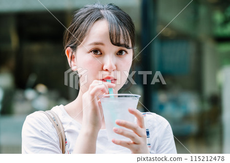 Young woman drinking water outdoors 115212478