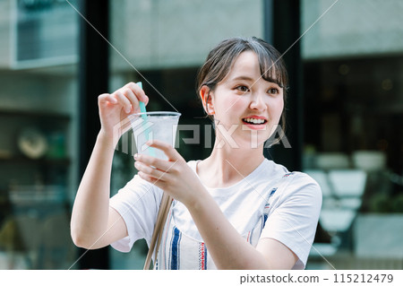 Young woman drinking water outdoors 115212479