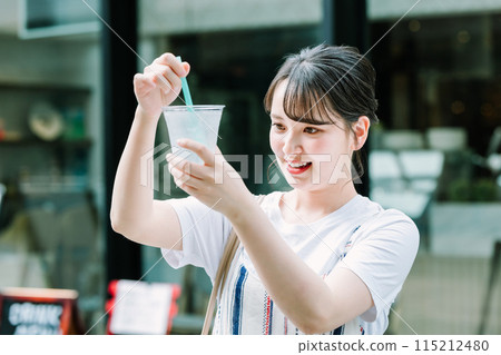 Young woman drinking water outdoors 115212480