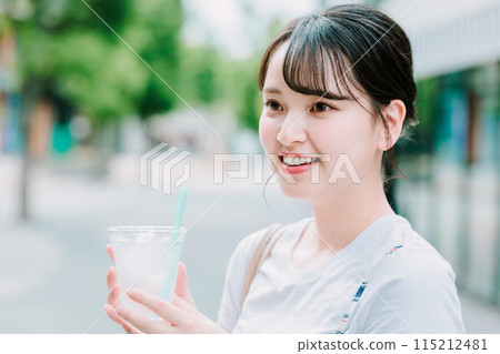 Young woman drinking water outdoors 115212481