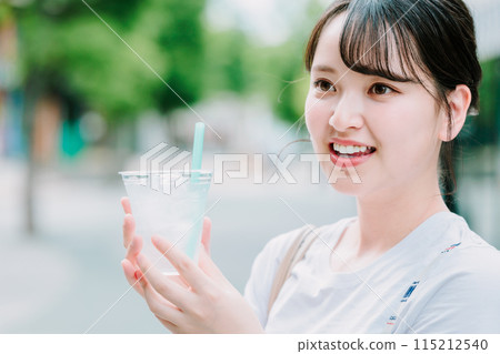 Young woman drinking water outdoors Young woman drinking water outdoors 115212540