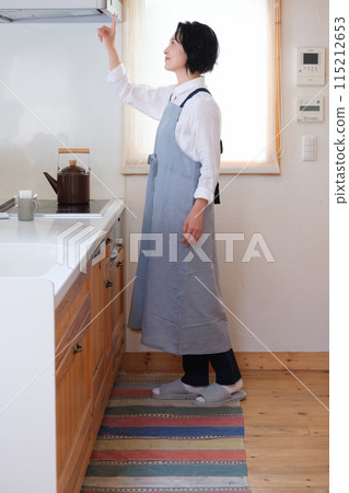 Portrait of a middle-aged woman standing in the kitchen 115212653