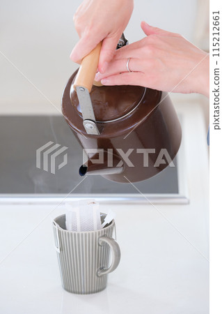 中年婦女的手將熱水倒入滴濾咖啡中 中年婦女的手將熱水倒入滴濾咖啡中 115212661