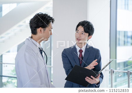Smiling male doctor and medical representative having a conversation at the hospital Smiling male doctor and medical representative having a conversation at the hospital 115212833