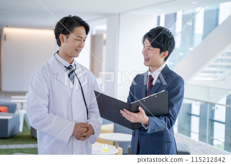 Smiling male doctor and medical representative having a conversation at the hospital Smiling male doctor and medical representative having a conversation at the hospital 115212842