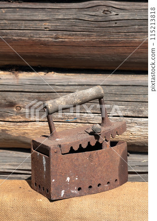 Rare iron working on coals. It stands on the background of an old wooden barn. It stands on a coarse cloth. Rare iron working on coals. It stands on the background of an old wooden barn. It stands on a coarse cloth. 115213818