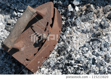 Rare iron working on coals. Against the background of extinct coals. Rare iron working on coals. Against the background of extinct coals. 115213820