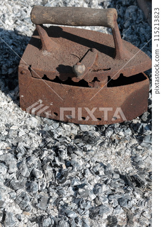 Rare iron working on coals. Against the background of extinct coals. 115213823