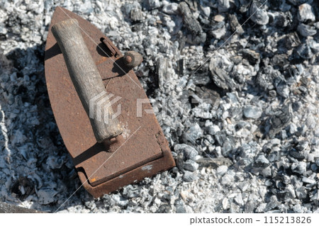 Rare iron working on coals. Against the background of extinct coals. Rare iron working on coals. Against the background of extinct coals. 115213826