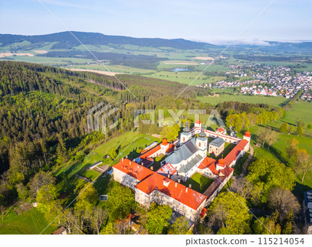 An aerial view of Hora Matky Bozi Monastery, located in Dolni Hedec near Kraliky, Czechia. The monastery is surrounded by lush greenery and a scenic landscape. 115214054