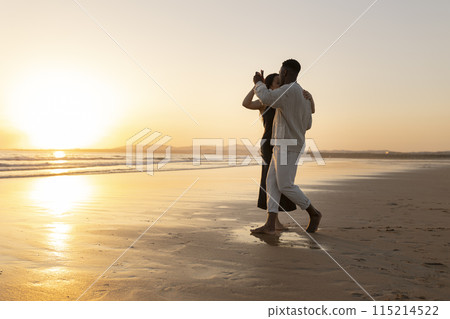A couple is dancing on the beach at sunset A couple is dancing on the beach at sunset 115214522