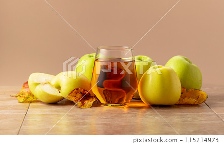 Apple juice and ripe apples with dried-up leaves. Apple juice and ripe apples with dried-up leaves. 115214973