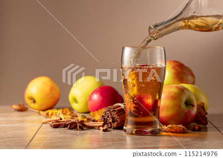 Apple cider is poured into a glass. Apple cider is poured into a glass. 115214976