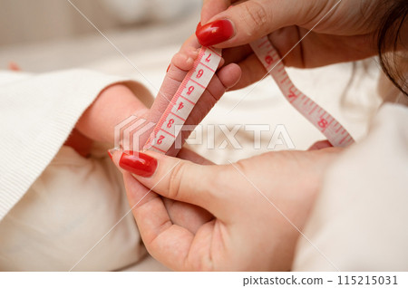 mother measures the size of a newborn baby's feets, close-up 115215031