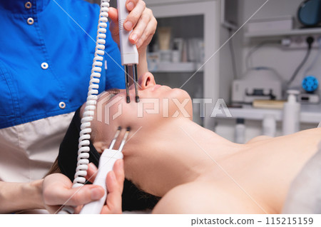 Close-up of a woman receiving an electric neck massage with equipment in a beauty salon. Used for therapy with a multifunctional electro massage device 115215159