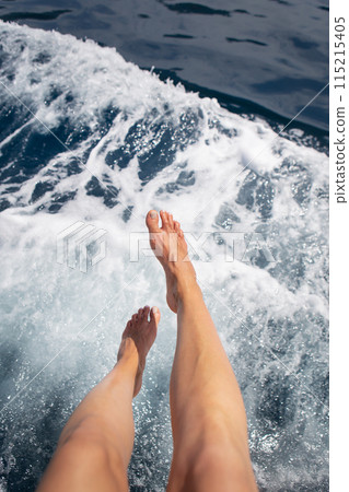 A close-up of a girl's bare feet over splashing sea water, capturing the essence of summer and relaxation. A close-up of a girl's bare feet over splashing sea water, capturing the essence of summer and relaxation. 115215405