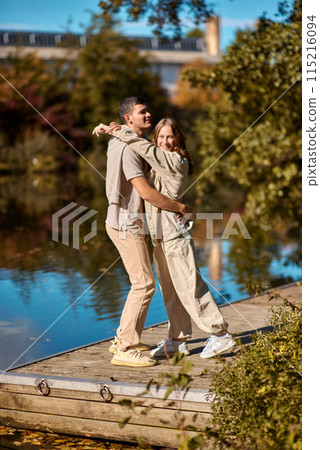 A happy couple in love in casual clothes travel together, hike and have fun in the fall forest on a weekend in nature in autumn outdoors, selective focus. COUPLE LOVE STORY park pond lake. Handsome 115216094